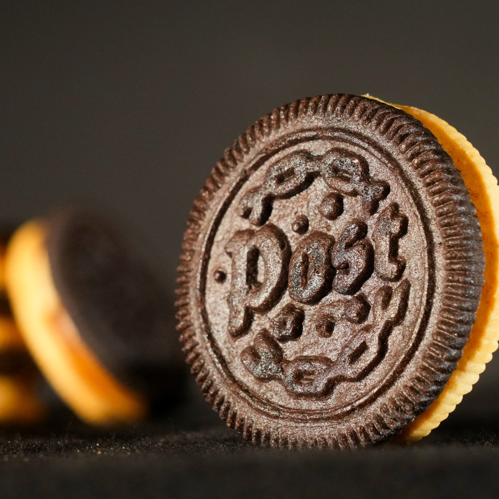 Detailed view of a single Post Malone Oreo cookie with custom 'Post' embossing and visible layered creme.