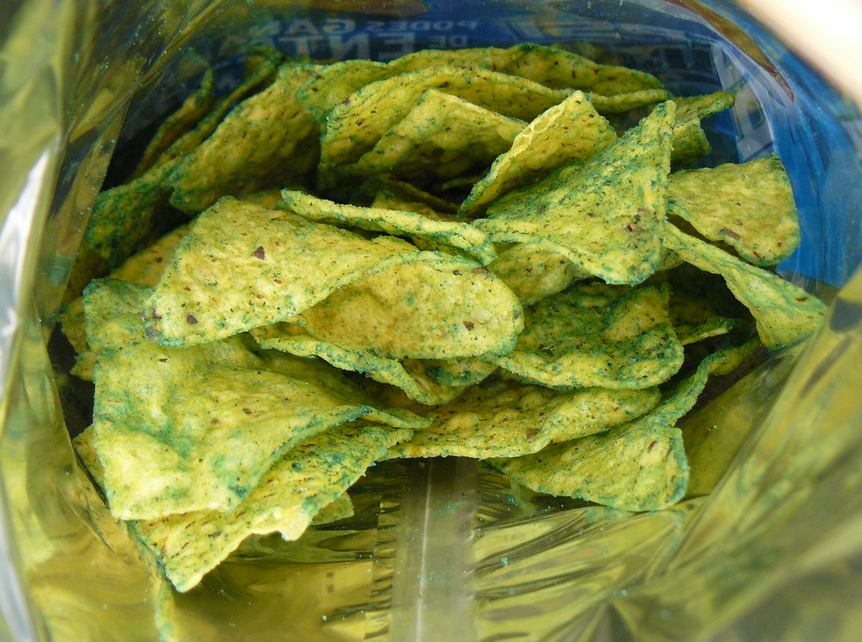 Close-up of Guacamole Doritos chips with green seasoning inside an open bag