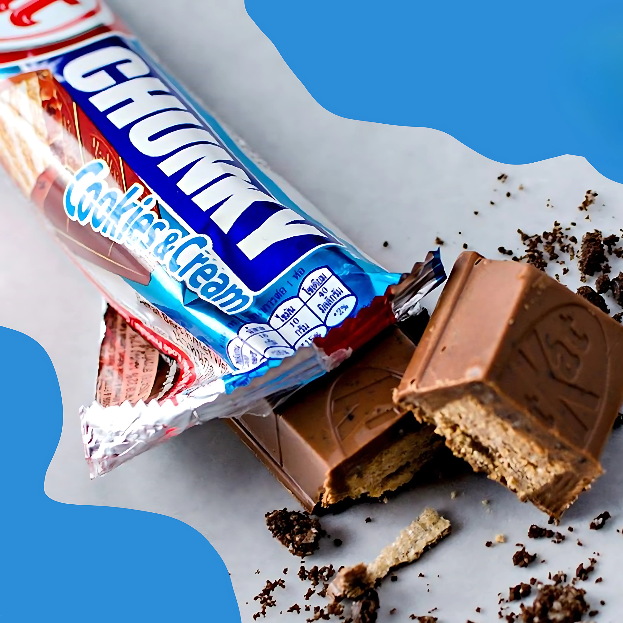 Unwrapped KitKat Chunky Cookies & Cream bar with broken pieces showing creamy wafer layers and cookie crumbs on a gray surface.