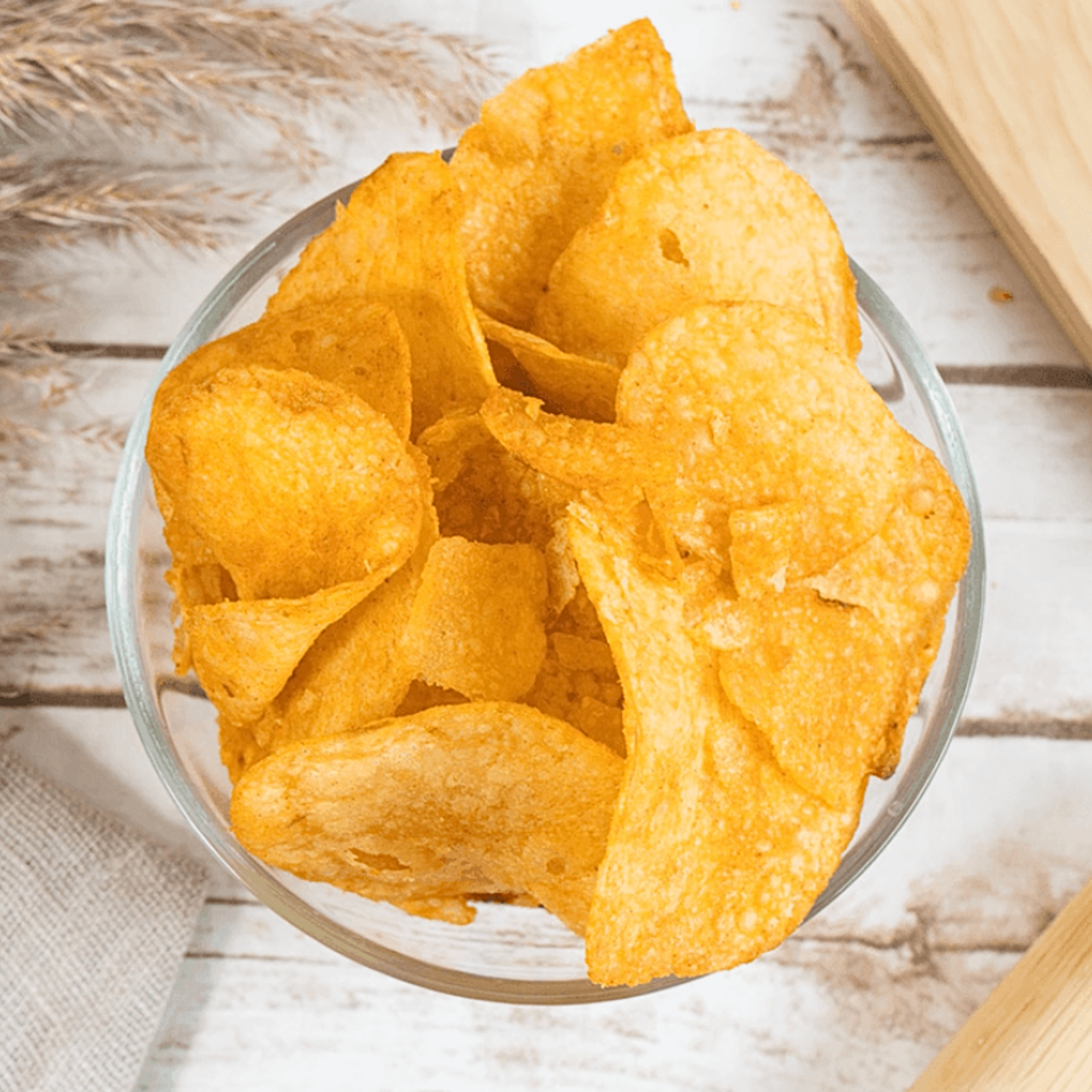 Golden Lay’s chips in a glass bowl with a rustic background, highlighting crispiness and seasoning.