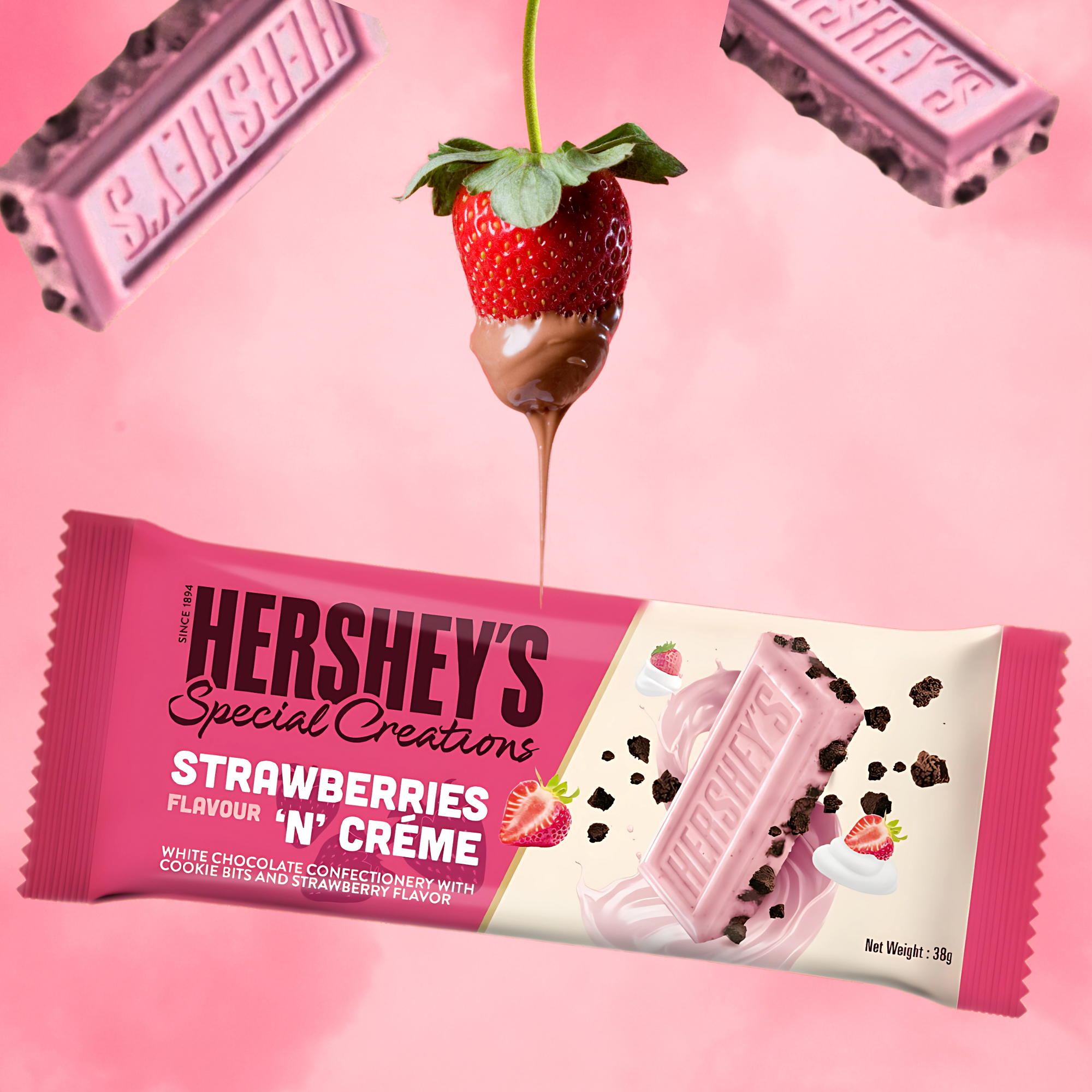 Hershey's Strawberries 'n' Creme candy bar on pink background. Strawberry dipped in chocolate and chocolate pieces surround the bar.