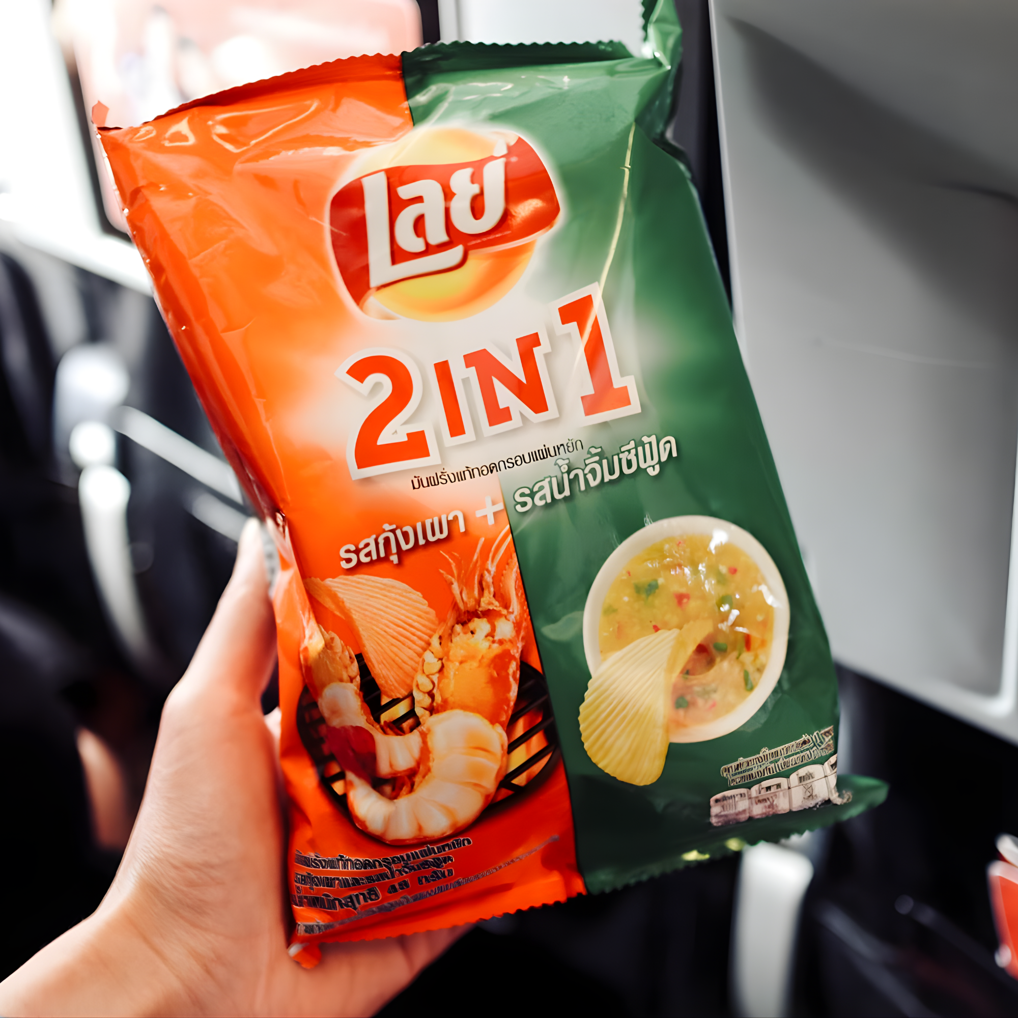 A hand holds a bag of Lay's 2-in-1 grilled shrimp and seafood flavors chips with a vibrant red and green package, featuring shrimp and seafood soup images. 