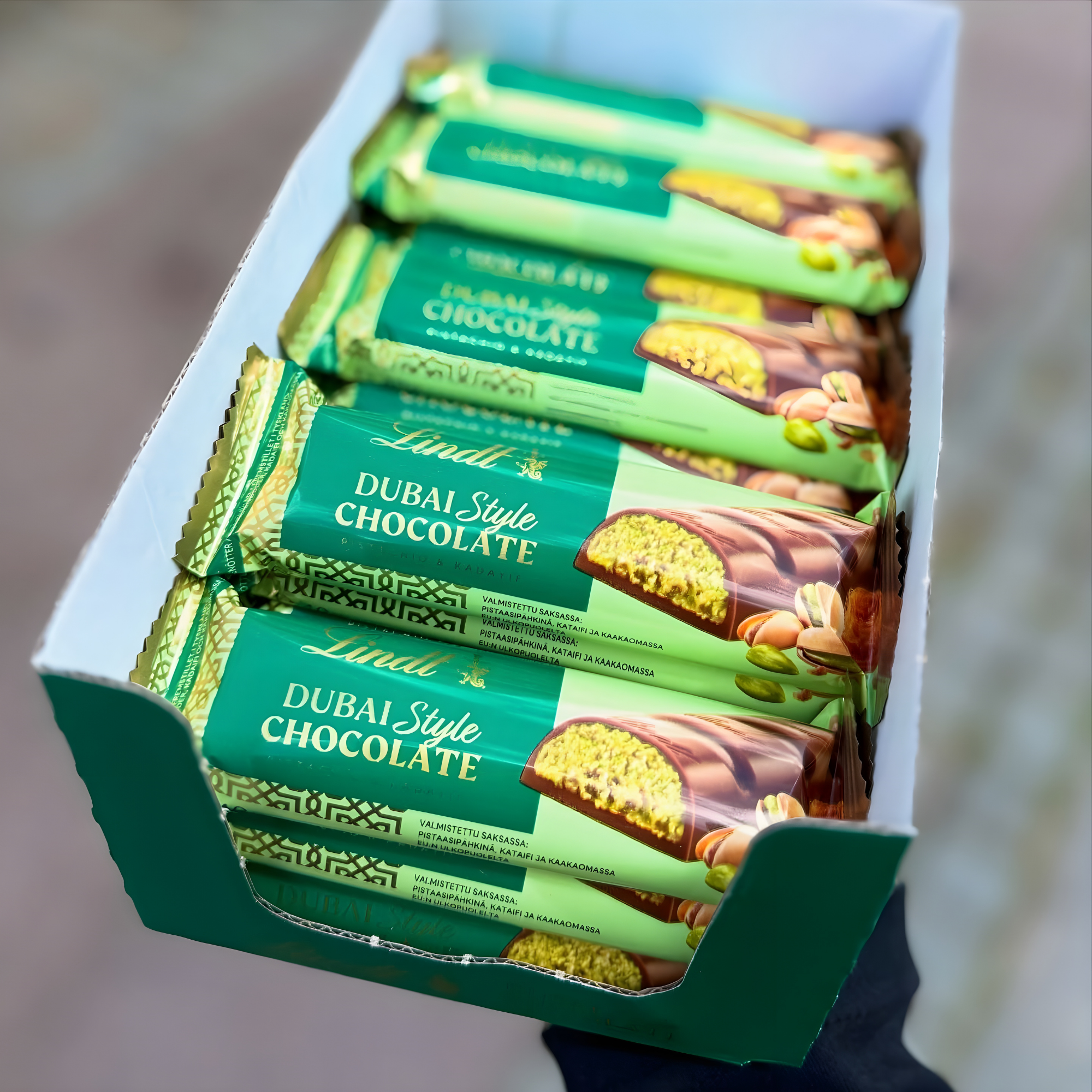 A box of Dubai Style Chocolate bars with green packaging, shows an image of chocolate with nuts.