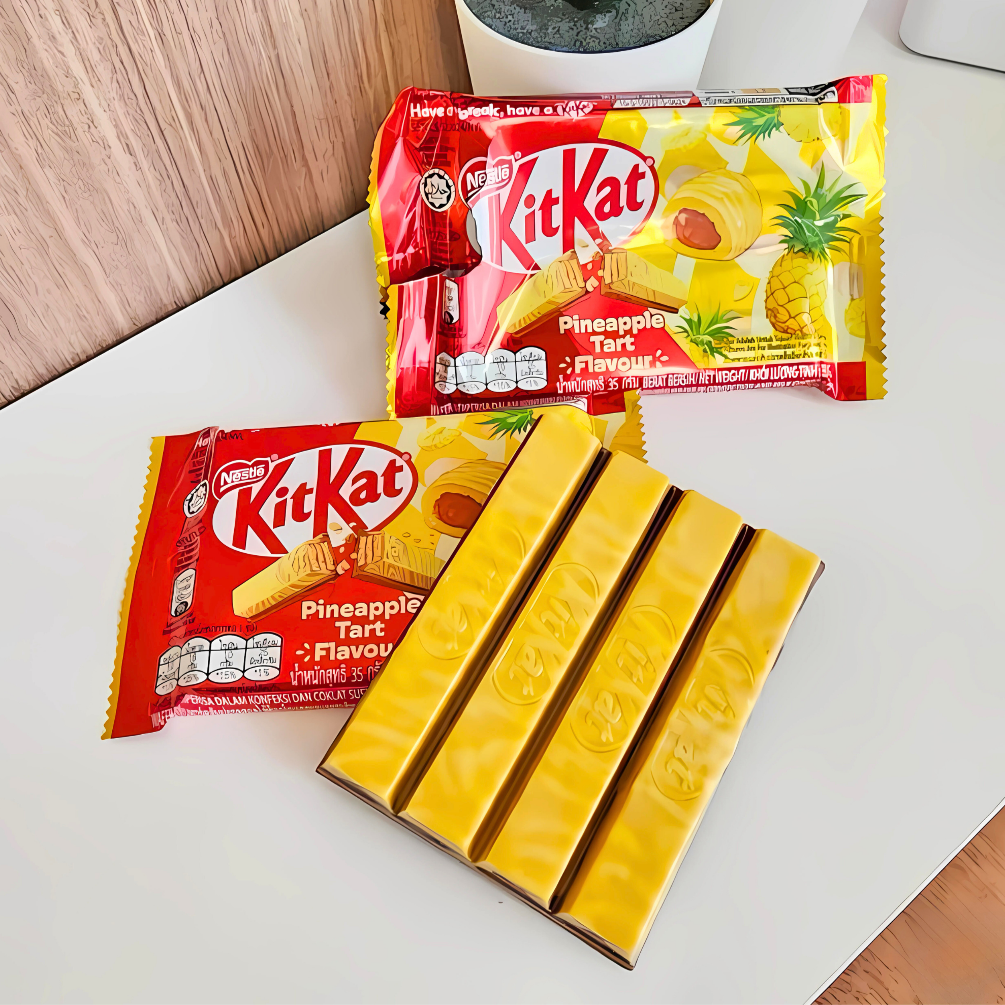 KitKat Pineapple Tart bars unwrapped and displayed on a white tabletop next to the packaging