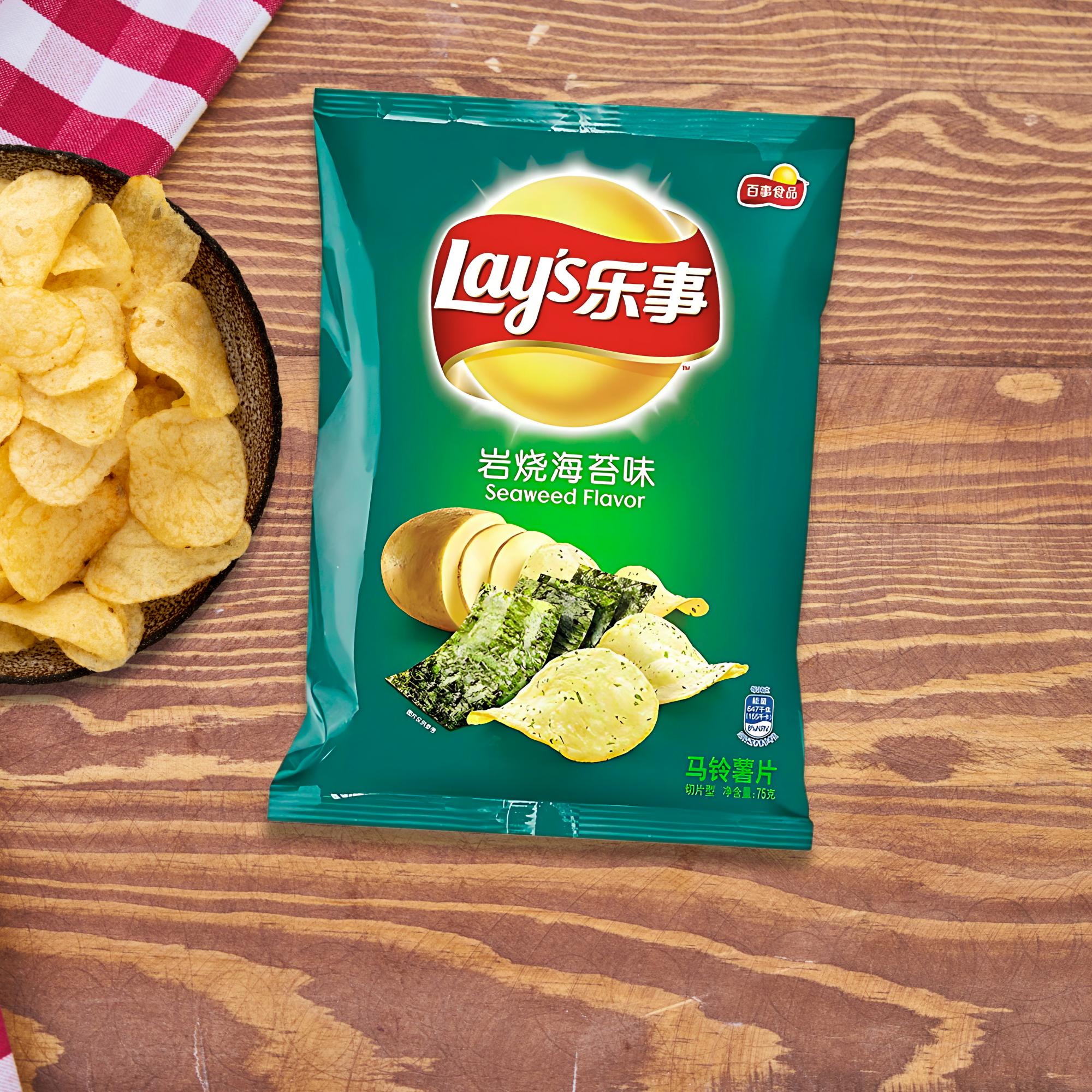 A green bag of Asian Lay's Seaweed Flavor chips lies on a wooden surface. Beside it is a bowl of chips. 