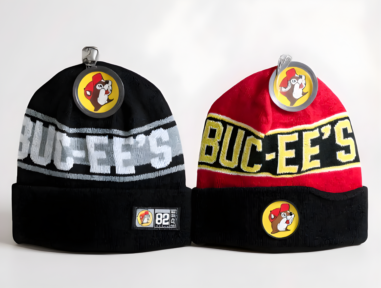 Two Buc-ee’s unisex knit beanies in gray and red colorways featuring knit Buc-ee’s lettering and the beaver logo on a white background