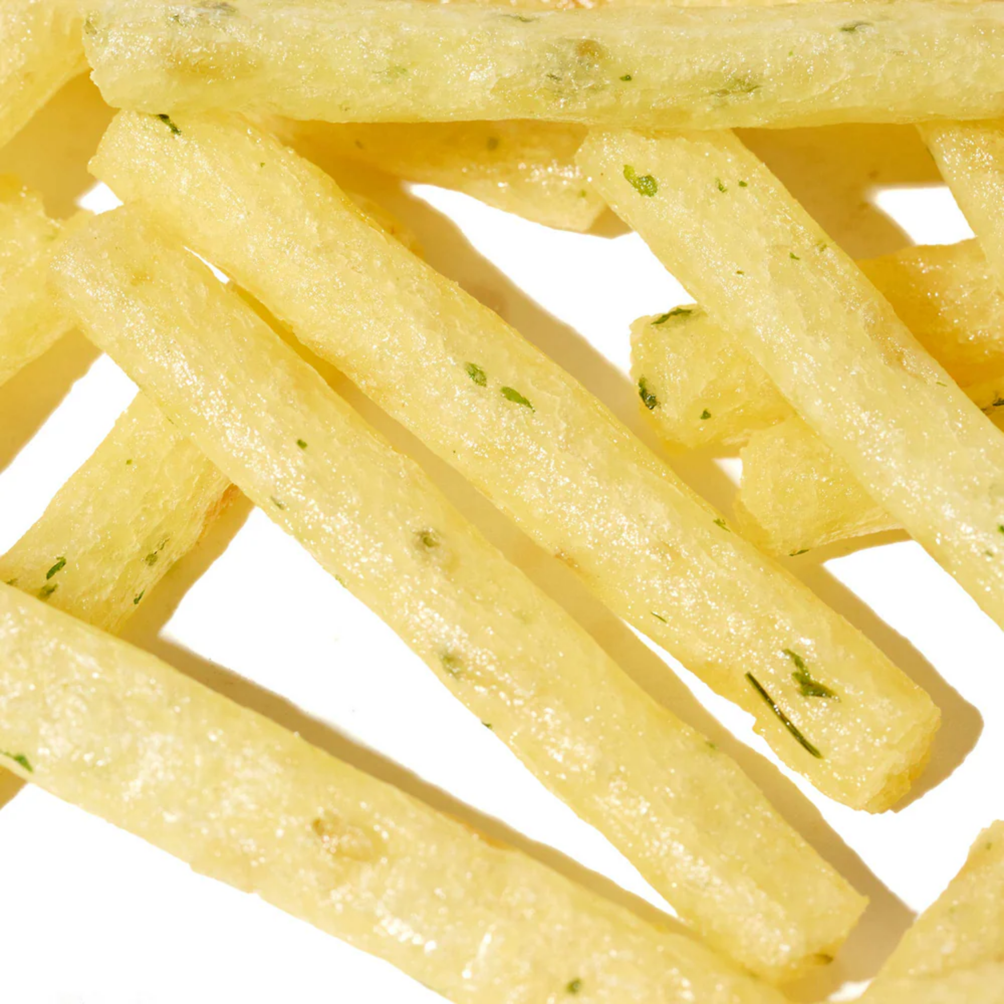 Close-up of light, crispy Calbee Hokkaido Butter potato sticks with a hint of green seasoning. The sticks are arranged randomly against a white background, evoking a savory snack vibe. Buy asian snack box online.