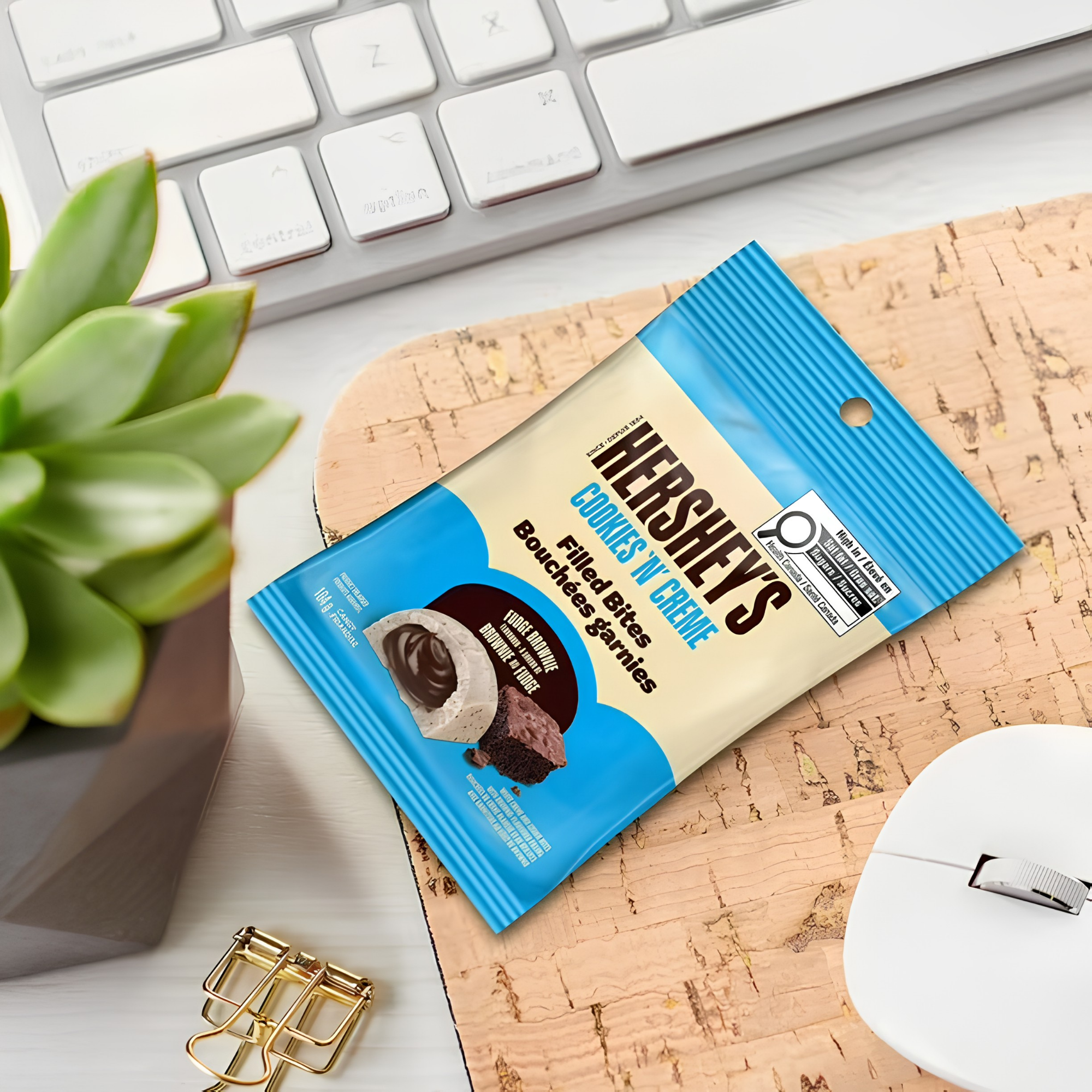 Pack of Hershey's Cookies N Creme Filled Bites from Canada on a mat with a keyboard and mouse visible. Shop Canadian candy online.