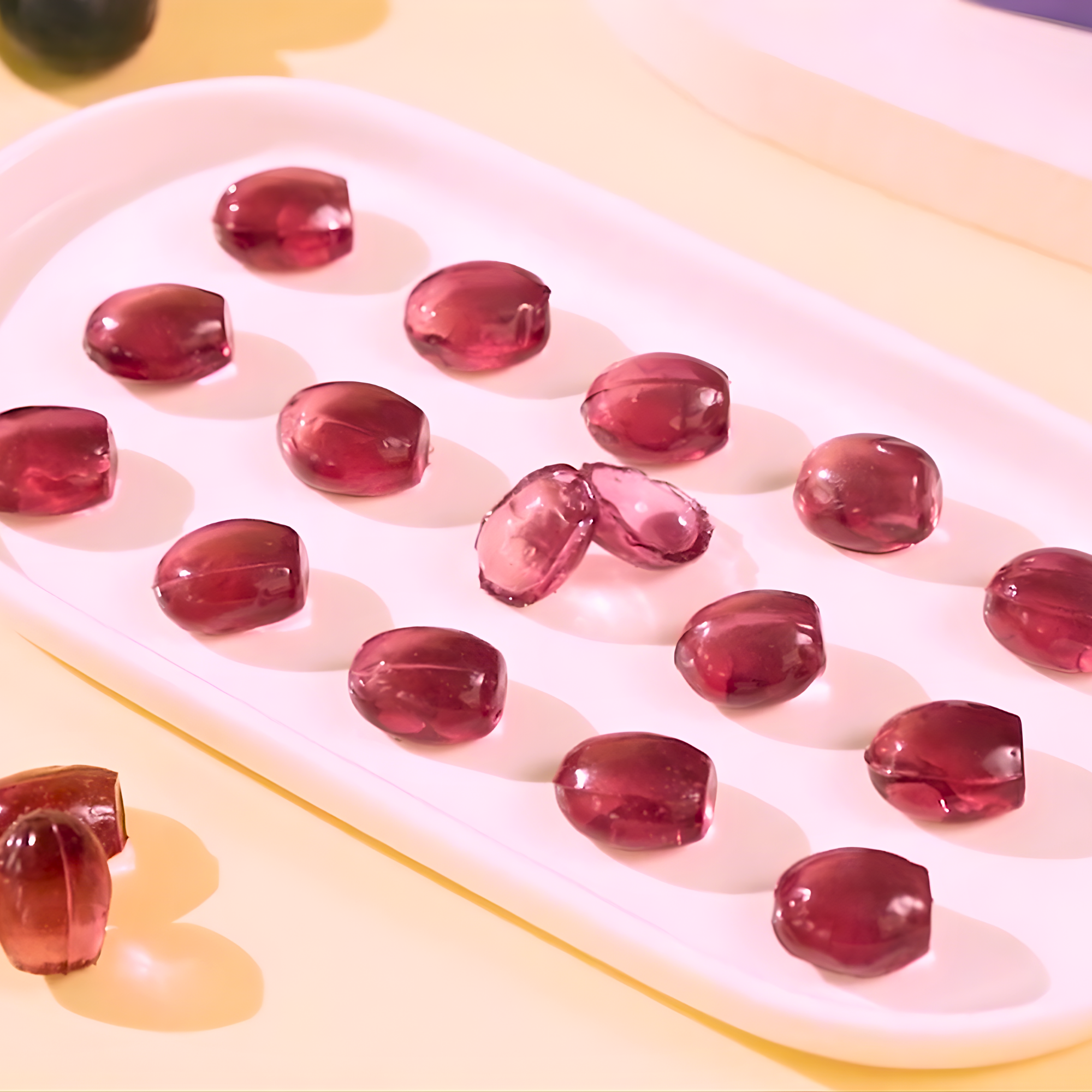 Several KOZED peelable grape gummies from China are arranged on a white tray. Buy peelable candy online.