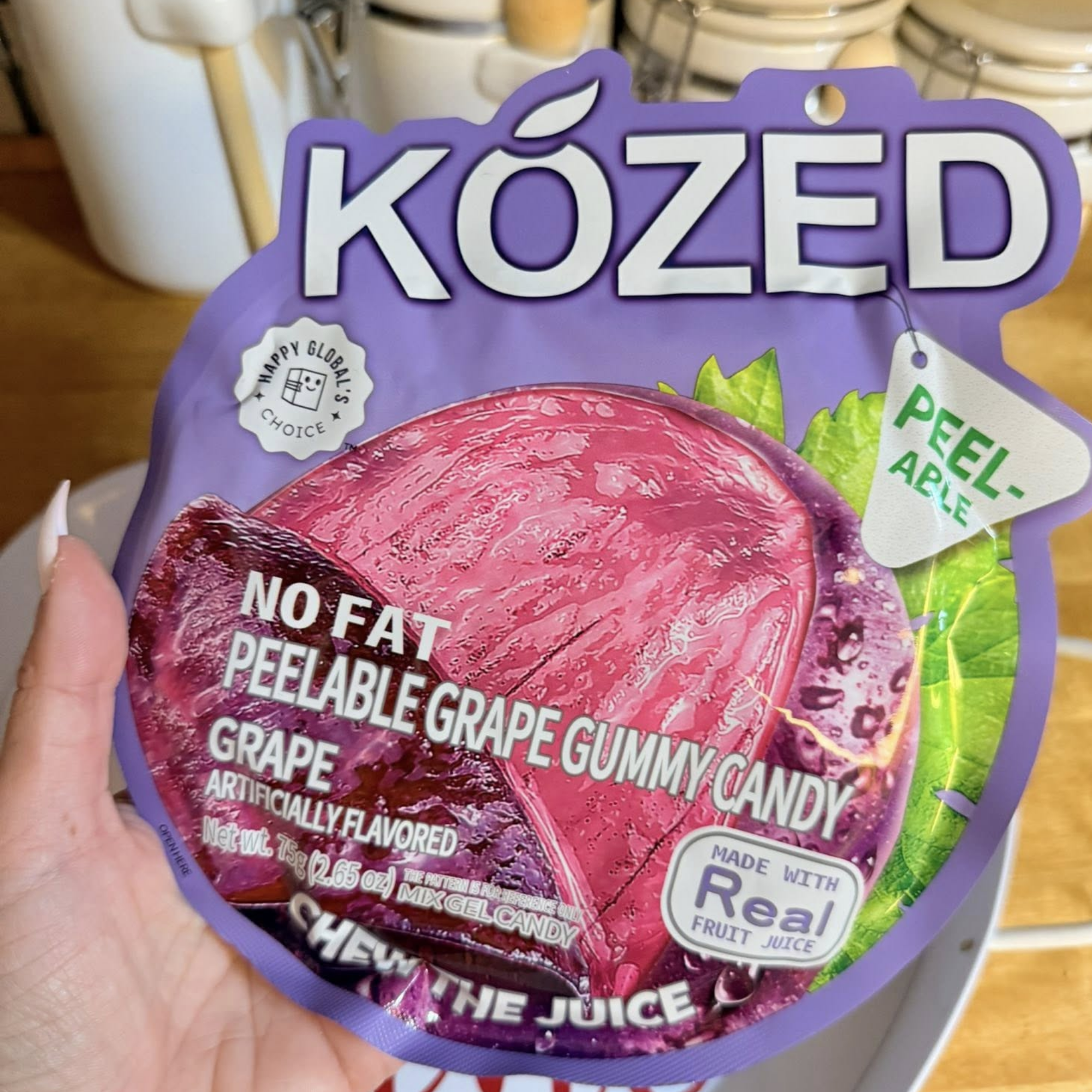 Close-up of a purple bag of KOZED peelable grape gummy candy from China. The package is labeled "no fat" with emphasis on "real fruit juice" and "peelable." Buy asian snack box online.