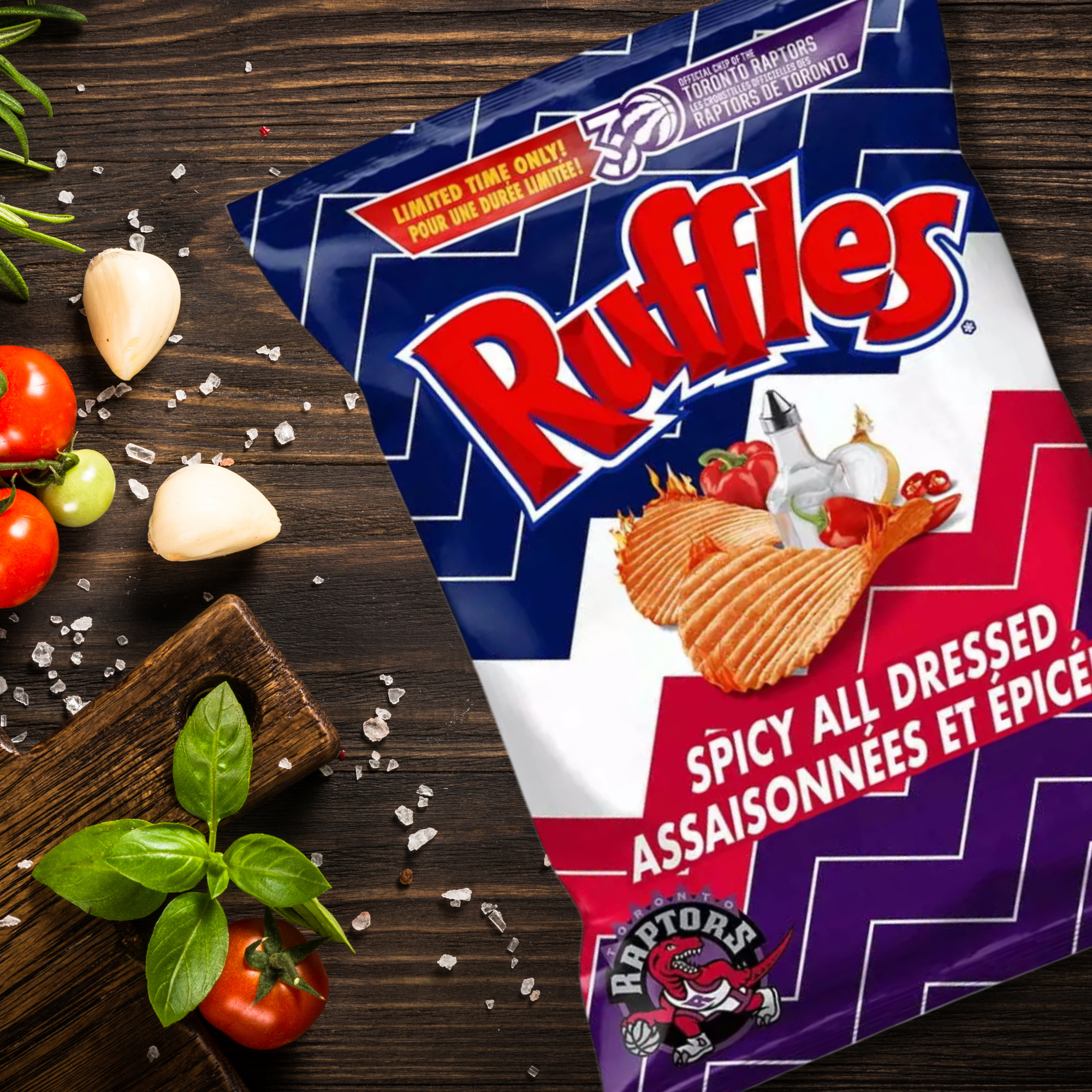 Ruffles Spicy All Dressed potato chips packaging on a wooden surface with ingredients.