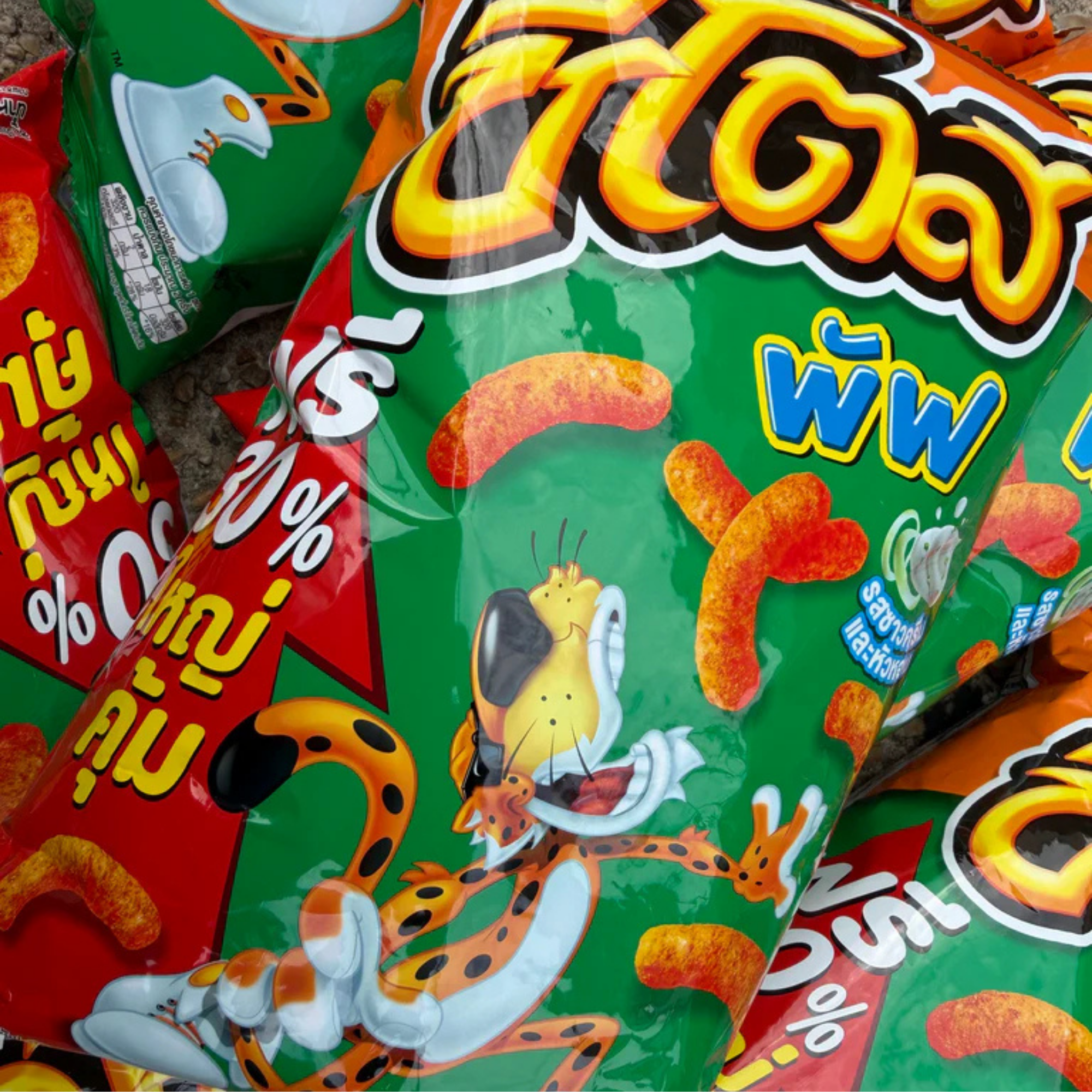 Close-up of a Thai Sour Cream and Onion Cheetos bag featuring a playful cartoon cheetah, surrounded by bright red and green designs with Thai text and cheesy puffs.