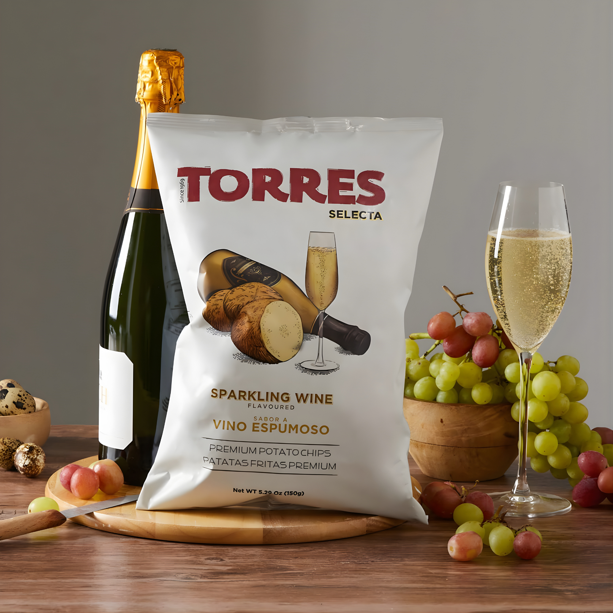 Bag of Torres Selecta sparkling wine-flavored potato chips from Spain on a wooden surface, surrounded by a champagne bottle, a filled flute, grapes and quail eggs.